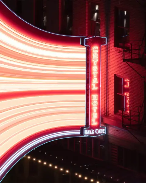 A photo of a neon sign in Portland Oregon, This one with a special effect applied to streatch the sign across the street below.